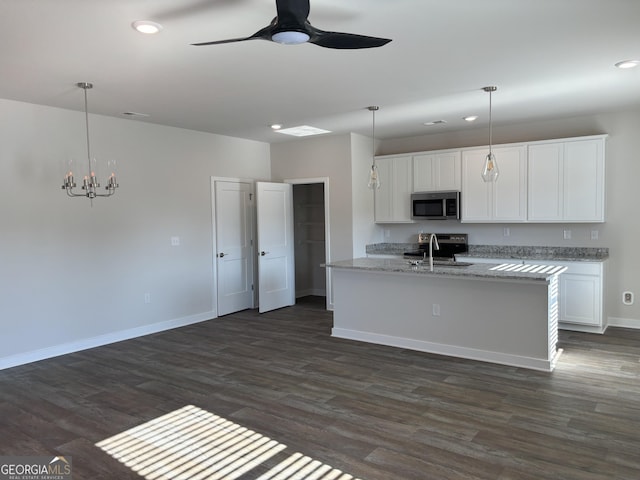 kitchen with decorative light fixtures, an island with sink, white cabinets, stainless steel appliances, and light stone countertops