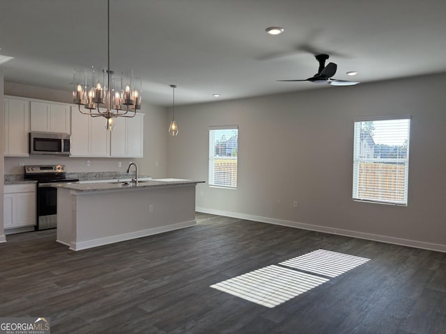 kitchen with dark wood-type flooring, white cabinetry, decorative light fixtures, appliances with stainless steel finishes, and an island with sink