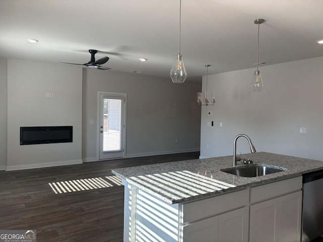 kitchen featuring decorative light fixtures, dishwasher, white cabinetry, sink, and light stone countertops