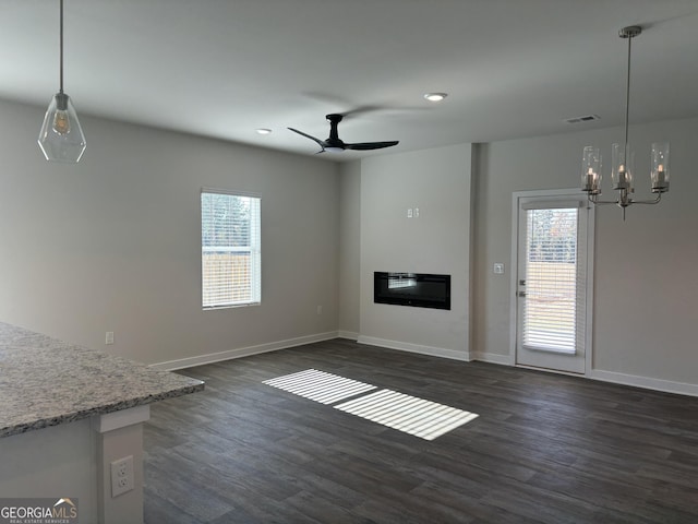 unfurnished living room with dark wood-type flooring, plenty of natural light, and ceiling fan