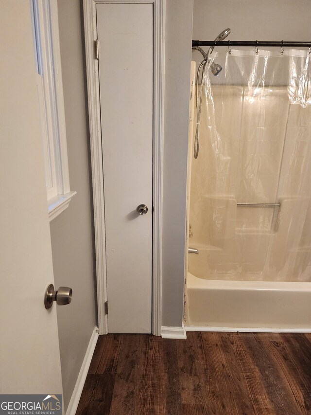 bathroom with shower / bathtub combination with curtain and hardwood / wood-style flooring