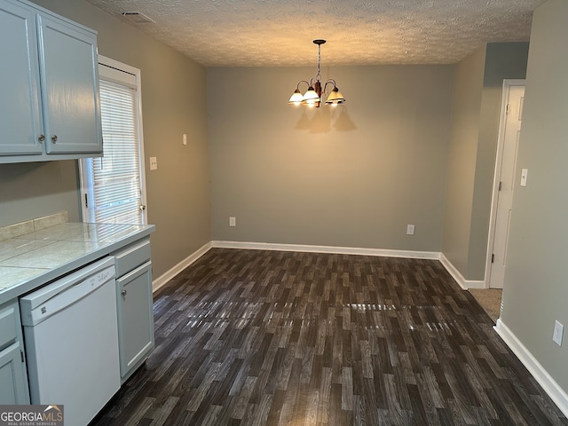 unfurnished dining area featuring dark hardwood / wood-style flooring, a textured ceiling, and an inviting chandelier