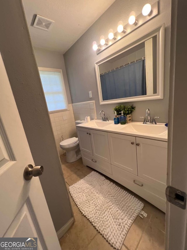 bathroom featuring vanity, tile patterned floors, a shower with shower curtain, toilet, and tile walls