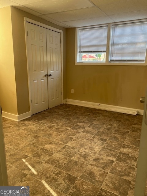 unfurnished bedroom with a paneled ceiling and a closet