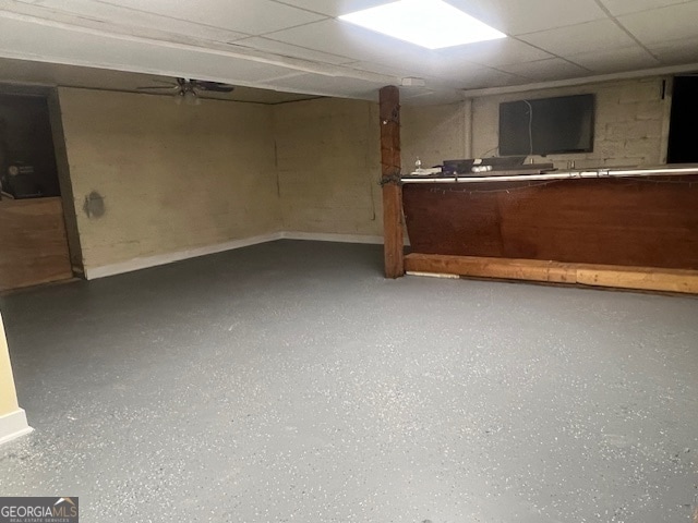 basement with a paneled ceiling and ceiling fan