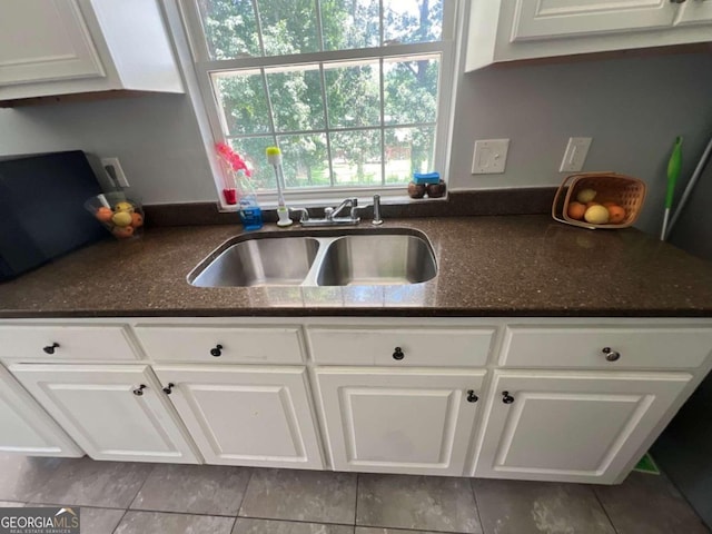 kitchen with light tile patterned floors, white cabinetry, and sink