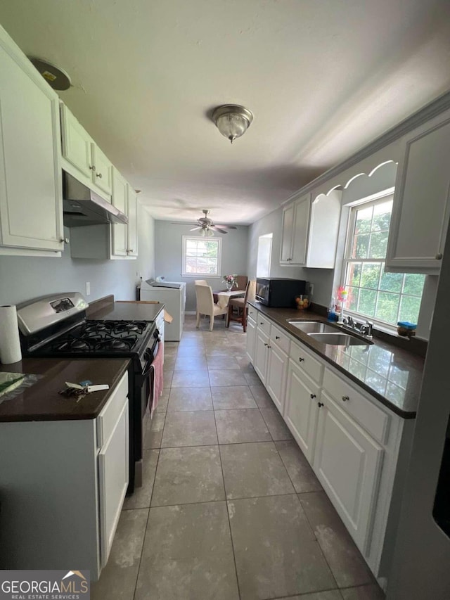 kitchen featuring white cabinets, washer and clothes dryer, black gas stove, and a wealth of natural light