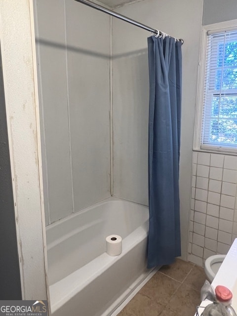 bathroom featuring toilet, tile patterned flooring, tile walls, and shower / tub combo with curtain