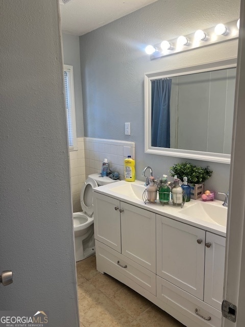 bathroom with tile patterned flooring, vanity, tile walls, and toilet