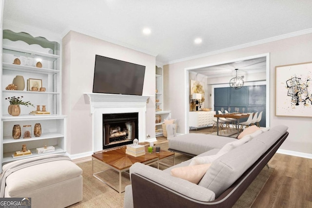 living room featuring hardwood / wood-style flooring, a notable chandelier, ornamental molding, and built in shelves