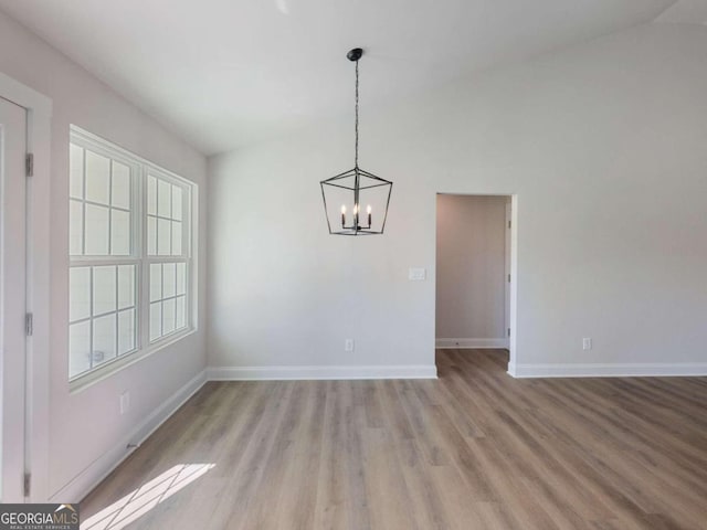 unfurnished dining area with a chandelier, lofted ceiling, and light wood-type flooring