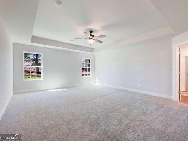 spare room featuring light colored carpet, ceiling fan, and a healthy amount of sunlight