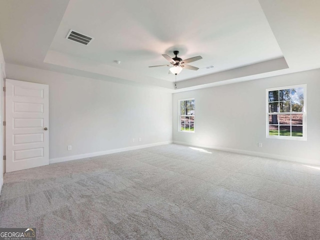 unfurnished room with carpet, ceiling fan, and a tray ceiling