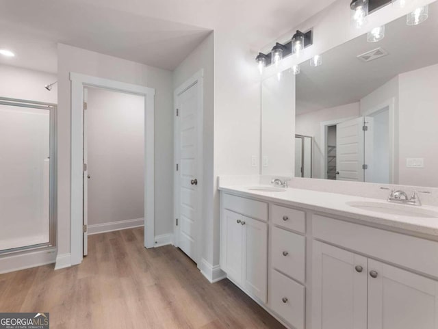 bathroom with vanity, hardwood / wood-style flooring, and a shower with door