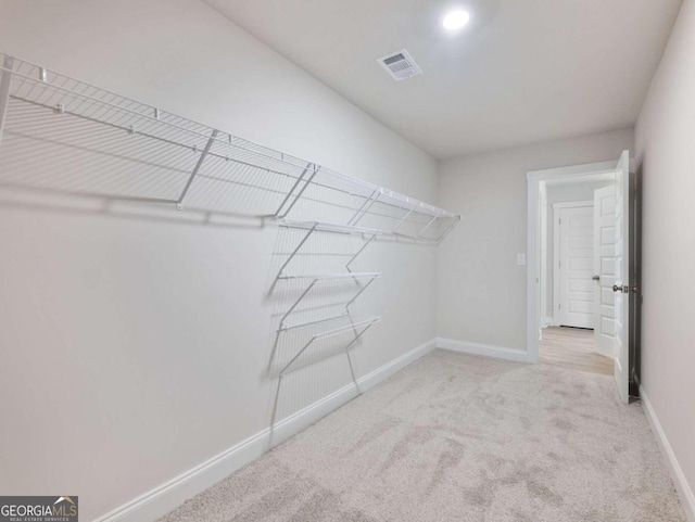 walk in closet featuring light colored carpet