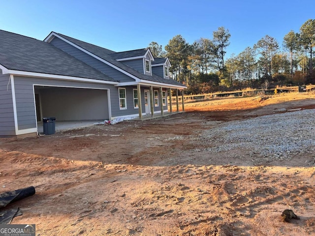 view of property exterior with covered porch and a garage