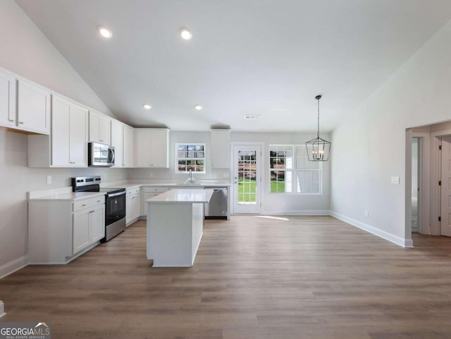 kitchen featuring stainless steel appliances, wood-type flooring, white cabinets, a center island, and hanging light fixtures