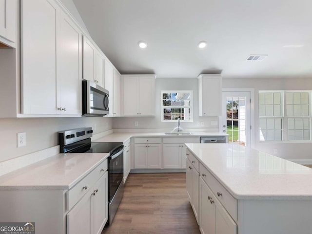 kitchen featuring light stone countertops, appliances with stainless steel finishes, dark wood-type flooring, sink, and white cabinetry