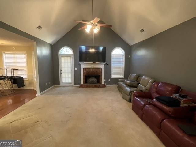 carpeted living room with ceiling fan, a fireplace, and high vaulted ceiling