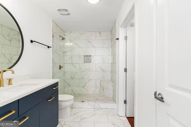 bathroom with tiled shower, vanity, and toilet