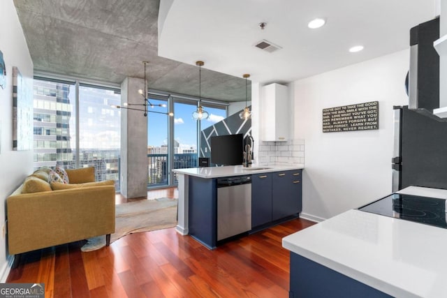 kitchen featuring decorative light fixtures, white cabinets, backsplash, stainless steel appliances, and dark wood-type flooring