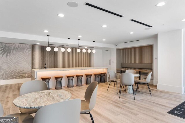 bar featuring light hardwood / wood-style floors and decorative light fixtures