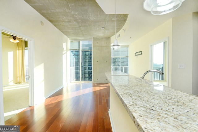 kitchen featuring dark hardwood / wood-style flooring, decorative light fixtures, light stone counters, and ceiling fan