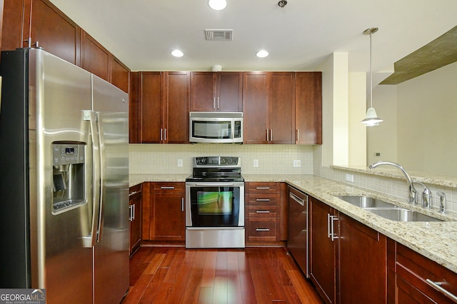 kitchen with sink, light stone counters, dark hardwood / wood-style flooring, decorative light fixtures, and appliances with stainless steel finishes