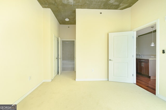 unfurnished bedroom featuring ensuite bathroom and light carpet