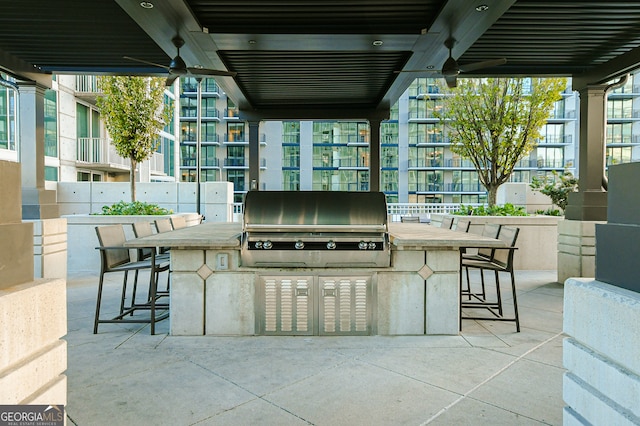 view of patio / terrace featuring a grill, ceiling fan, exterior bar, and an outdoor kitchen