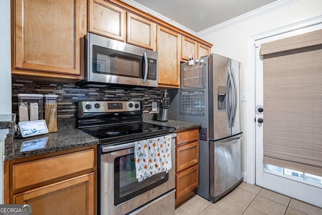 kitchen featuring backsplash, dark stone counters, stainless steel appliances, crown molding, and light tile patterned floors