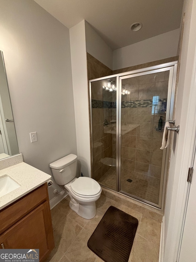 bathroom with tile patterned flooring, vanity, toilet, and a shower with shower door