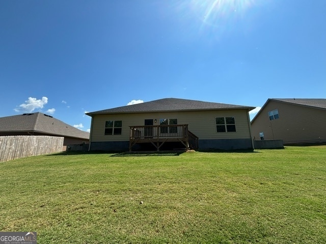 back of property with a yard and a wooden deck