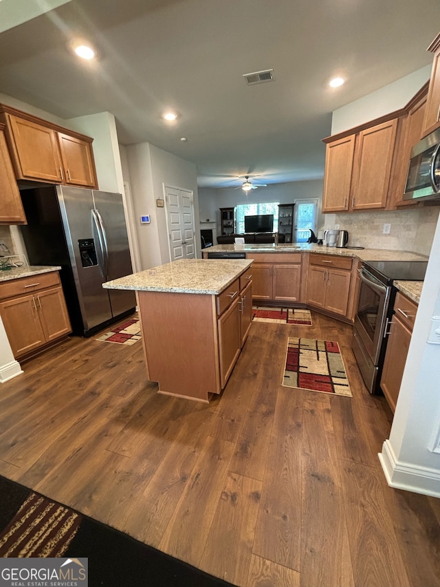 kitchen with kitchen peninsula, a center island, dark wood-type flooring, and appliances with stainless steel finishes