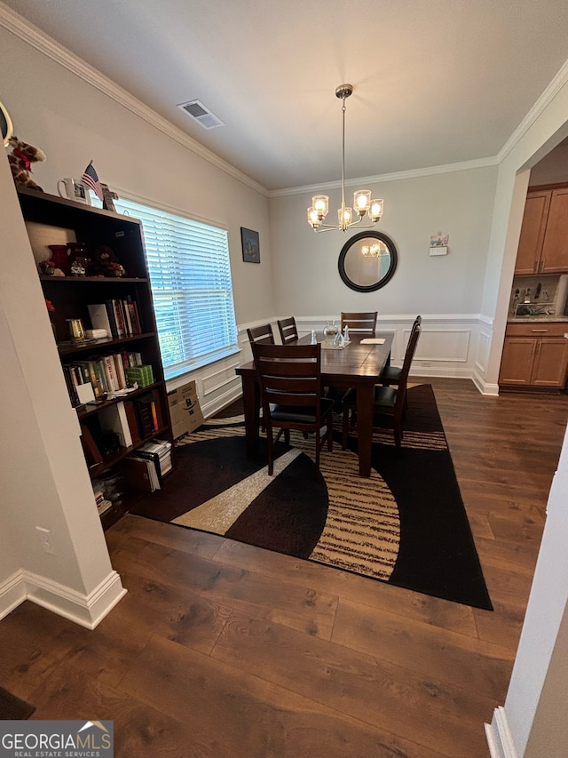 dining space with dark hardwood / wood-style flooring, an inviting chandelier, and crown molding