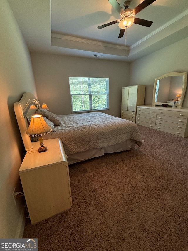 carpeted bedroom with ceiling fan, a raised ceiling, and crown molding