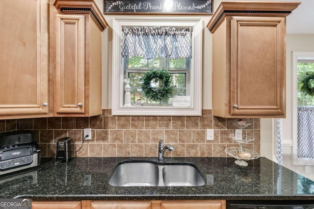 kitchen featuring decorative backsplash, black dishwasher, dark stone countertops, and sink