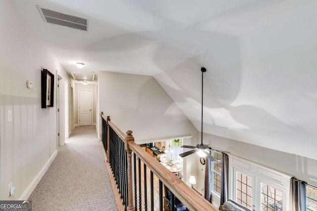 hall with a wealth of natural light, light colored carpet, and vaulted ceiling