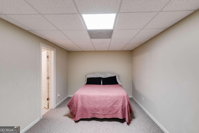 bedroom featuring a drop ceiling and carpet