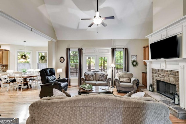 living room with ceiling fan with notable chandelier, light wood-type flooring, and a healthy amount of sunlight