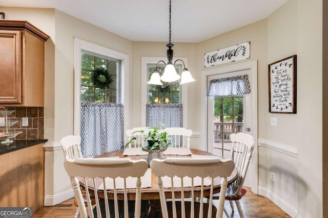 dining room featuring light hardwood / wood-style flooring, a healthy amount of sunlight, and a notable chandelier