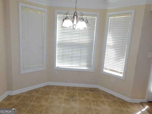 unfurnished dining area with tile patterned floors, a notable chandelier, plenty of natural light, and ornamental molding