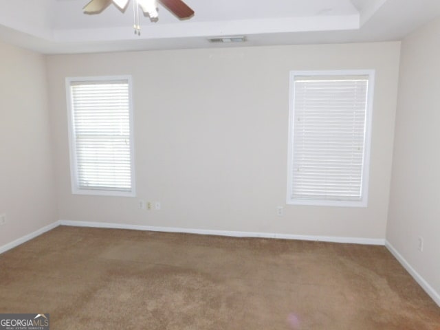 unfurnished room with carpet flooring, a raised ceiling, and ceiling fan