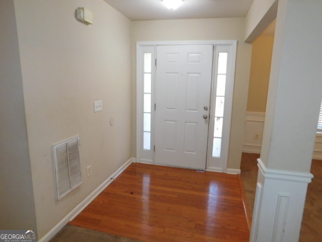 foyer entrance featuring decorative columns and dark hardwood / wood-style floors