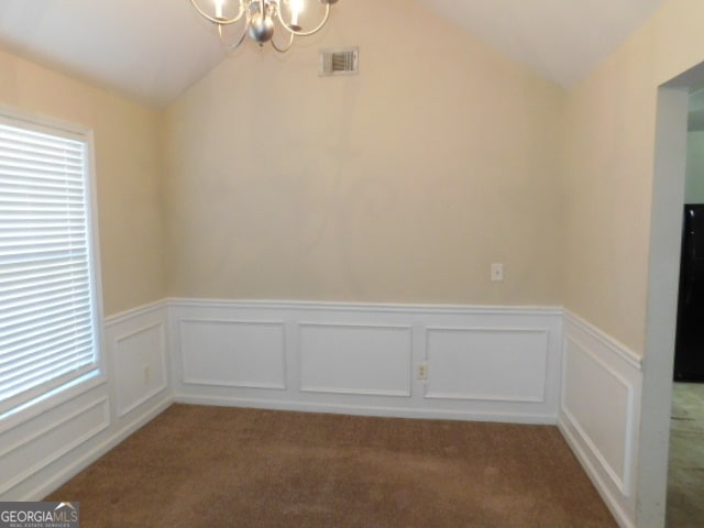 unfurnished room featuring dark colored carpet, a notable chandelier, and lofted ceiling