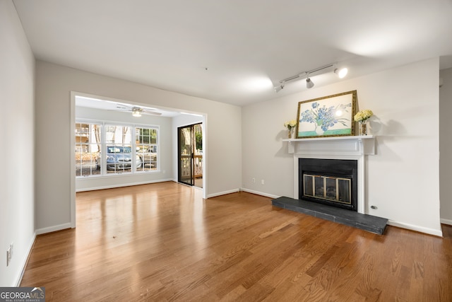 unfurnished living room featuring ceiling fan, hardwood / wood-style floors, and rail lighting