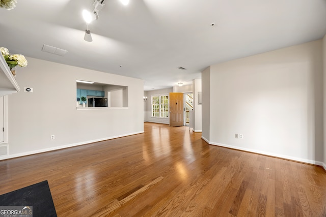 unfurnished living room with hardwood / wood-style floors and track lighting