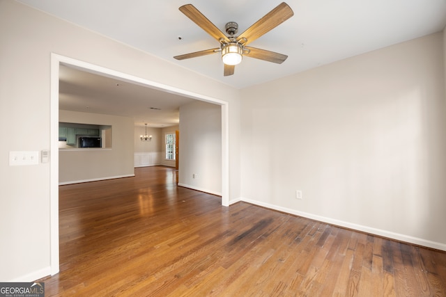 unfurnished room with hardwood / wood-style flooring and ceiling fan with notable chandelier