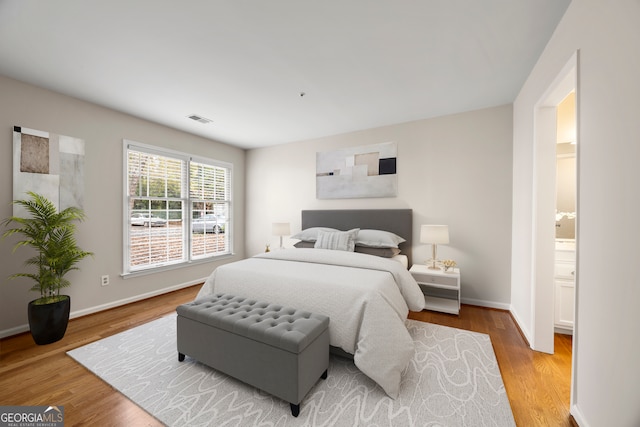 bedroom with connected bathroom and light hardwood / wood-style flooring