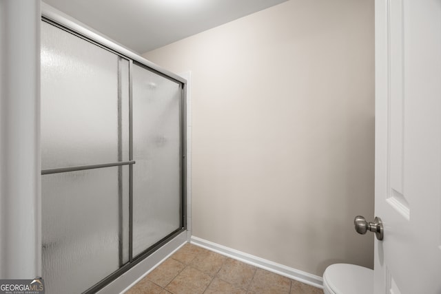 bathroom with tile patterned flooring, toilet, and a shower with door